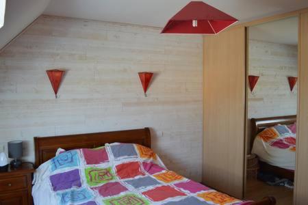 a bedroom with a bed with a mirror and a red lamp at Maison individuelle in Brette-les-Pins