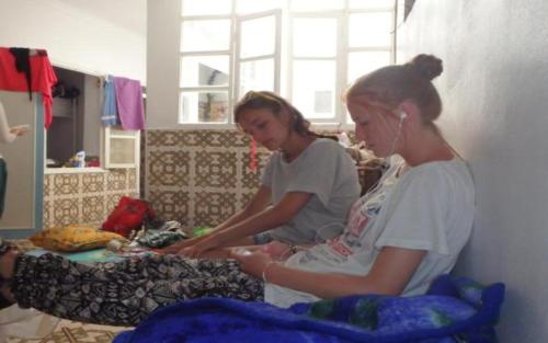 two women sitting on a bed in a room at White And Blue in Essaouira