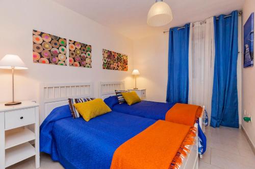 パルム・マールにあるLovely Apartamento El Palmarのベッドルーム1室(青とオレンジのベッド1台、青のカーテン付)