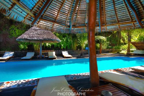 a swimming pool with chairs and an umbrella at L'heure Bleue in Ambatoloaka