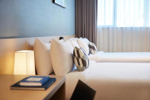 a hotel room with a bed with white pillows and a table at Days Hotel & Suites by Wyndham Incheon Airport in Incheon