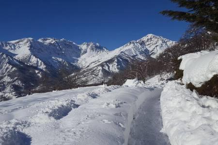 a snow covered road with mountains in the background at BARDONECCHIA SCI E RELAX in Bardonecchia