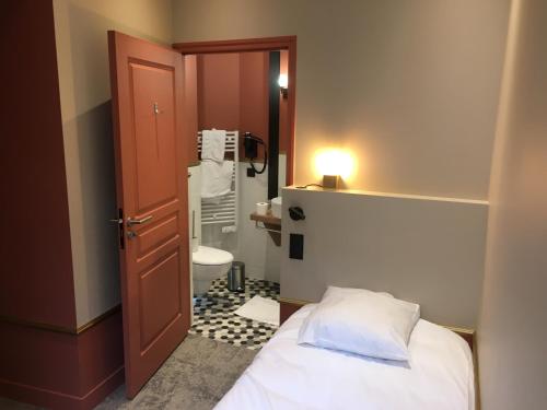 a small bathroom with a bed and a toilet at Hotel Brasserie Armoricaine in Saint Malo