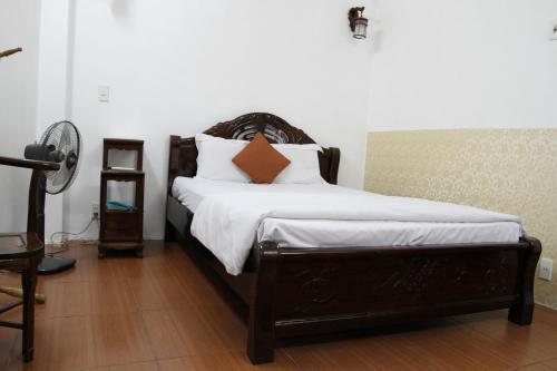 Schlafzimmer mit einem Bett mit weißer Bettwäsche und orangefarbenen Kissen in der Unterkunft Hoang Cuong Hotel in Hanoi