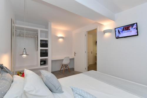 a bedroom with a white bed with a tv on the wall at Efi Studios in Drios
