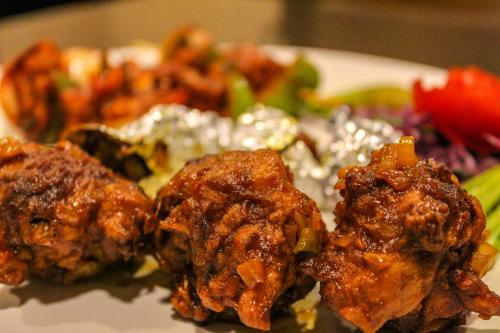 a white plate of food with meat and vegetables at Shankar Bhavan By Vinayak Hotels in Brahmapur