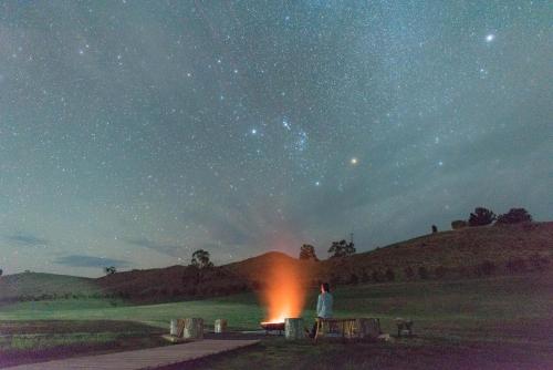 a man sitting on a bench looking at the night sky at Truffle Lodge Dinner Bed Breakfast Glamping in Gretna