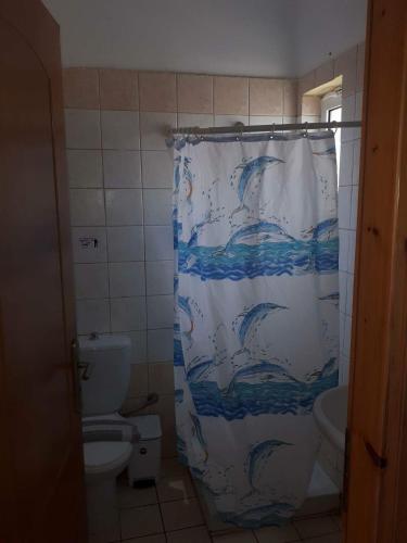 a bathroom with a shower curtain with dolphins on it at Gradma Katina in Platanias