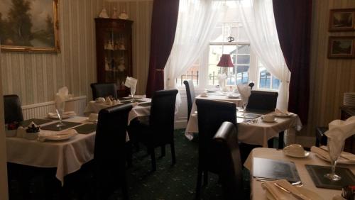 a dining room with tables and chairs and a window at The Bay Guest House in Weymouth