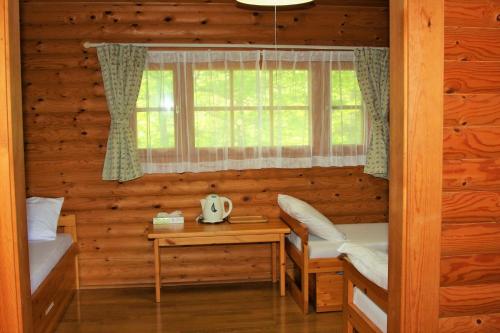 a room with two beds and a window in a log cabin at Shomarutoge Garden House in Hanno