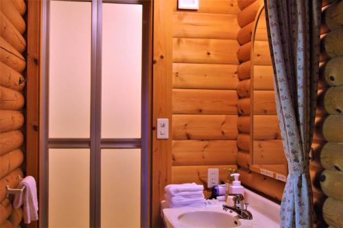 a bathroom with a sink and a shower in a log cabin at Shomarutoge Garden House in Hanno