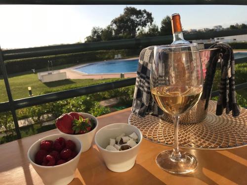 a glass of wine and a bowl of fruit on a table at Laukamao Mar a Vista in Portimão