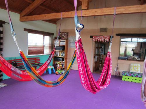 3 hamacs suspendus dans une pièce dotée de sols violets dans l'établissement Casa Rural Lamadretierra, à Villamejil