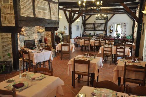 a restaurant with tables and chairs and a fireplace at Logis Hotels - Auberge de l'Île - Hôtel 3 étoiles et Restaurant in Creysse