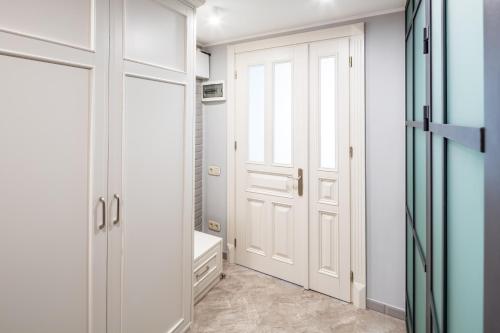 baño con armarios blancos y puerta en Romari апартименти площа Ринок, en Leópolis