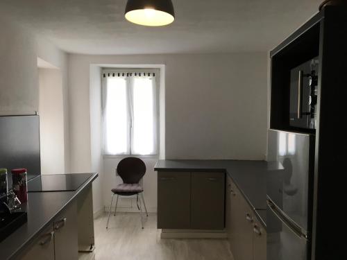 a kitchen with a black counter and a chair at Maison entière tout équipé 4 chambre possibilité de 10 couchage Venaco Centre Corse in Venaco
