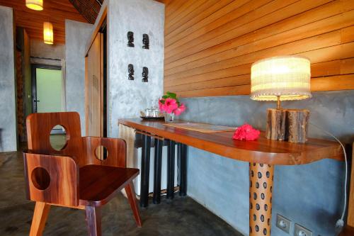 a table with a lamp and a chair in a room at L'heure Bleue in Ambatoloaka