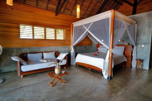 a bedroom with two beds and a couch in a room at L'heure Bleue in Ambatoloaka