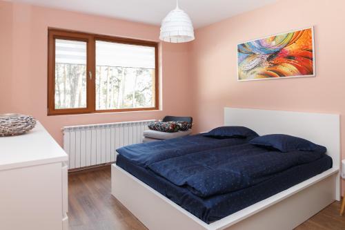 a bedroom with a large blue bed and a window at Апартамент "Forest view" в комплекс "Вели Хилс" in Velingrad