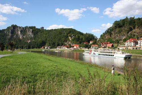 a boat on a river with a person standing in the grass at Ferienwohnung Am Grünbach 2 in Kurort Rathen