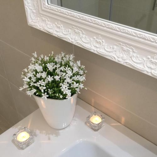a white vase with candles and flowers on a sink at Flowers Sweet Rooms B&B in Vasto