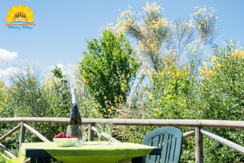 a table with a bottle of wine and two chairs at Casa in Maremma Tuscany Village in Scarlino
