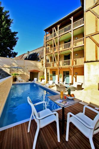 un patio avec deux chaises et une piscine dans l'établissement Hotel de Compostelle, à Sarlat-la-Canéda