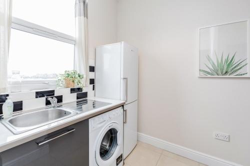 a kitchen with a sink and a washing machine at WelcomeStay Clapham Junction 2 Bedroom Apartment in London