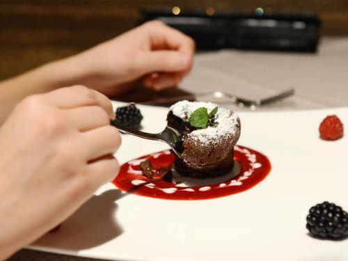 a person eating a dessert on a plate with a spoon at Hotel Purvita by Oberlechner in Maranza