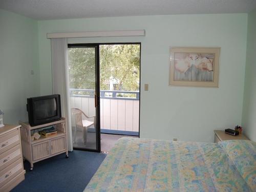 1 dormitorio con cama, TV y balcón en Summer Tree Village A11, en Myrtle Beach