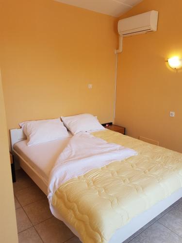a bed with white sheets and pillows in a room at Guest House Betiga in Barbariga