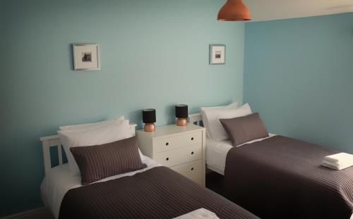 a bedroom with two beds and a dresser with two candles at Conwy Cottage in Conwy