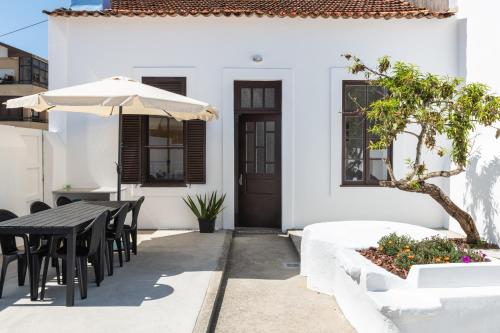 a white house with a black table and umbrella at Furadouro Surf Camp (House) in Ovar