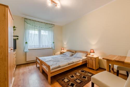 een slaapkamer met een bed, een bureau en een raam bij Pokoje Gościnne Mrągowo in Mrągowo