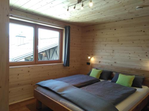 a bed in a wooden room with a window at Walser Berg Chalets in Riezlern