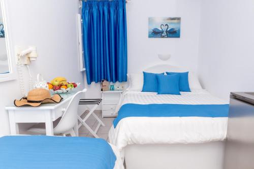 a bedroom with two beds and a table with a bowl of fruit at Margarita Hotel in Firostefani