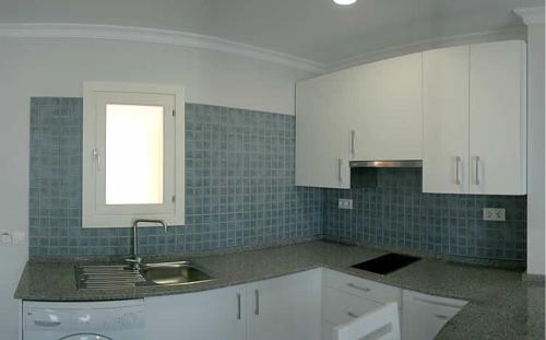 a kitchen with white cabinets and a sink and a window at Apartamentos Turísticos Gran Sol in Zahara de los Atunes