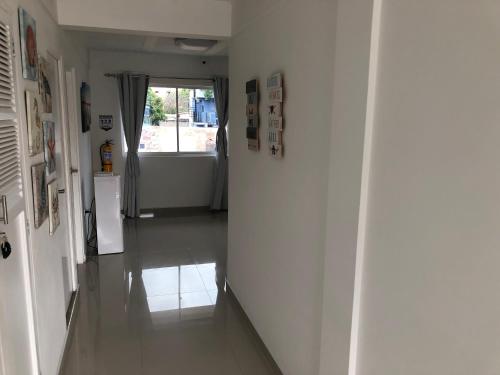 a hallway with white walls and a hallway with a window at Sashii Hostel & Boutique. in Ríohacha