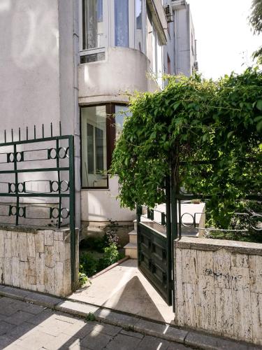 a house with a gate and a tree in front of it at Promenada Apartment in Constanţa