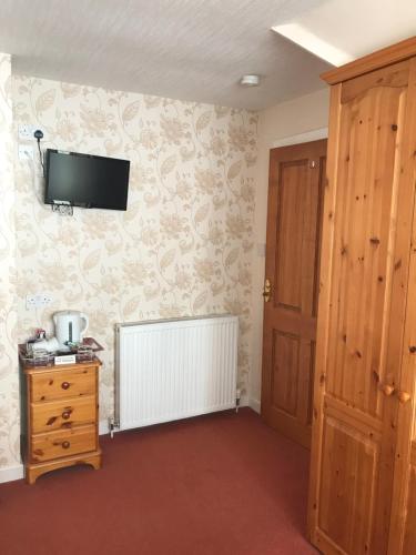 a room with a tv on the wall and a door at Wimberley House in Inverness