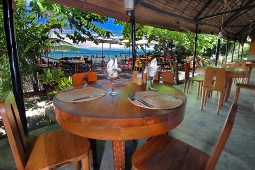 a wooden table in a restaurant with a view of the ocean at L'heure Bleue in Ambatoloaka