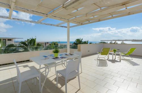 a patio area with chairs, tables, and tables with umbrellas at Kamena Residence in Marina di Ragusa