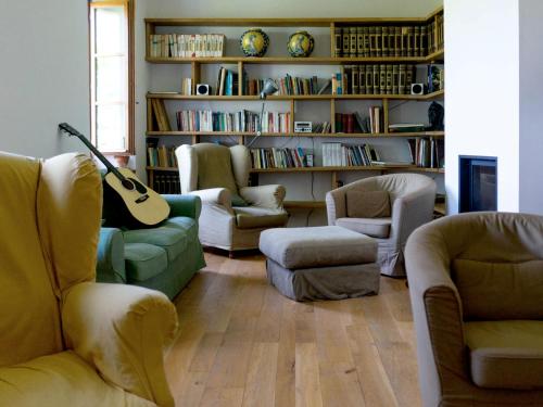 a living room with couches and a guitar in a library at Ostello Bello Assisi Bevagna in Bevagna