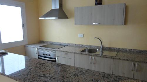 
a kitchen with a sink and a stove at Apartamentos Cala Llonga in Cala Llonga
