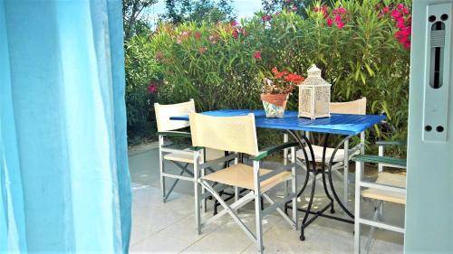 a blue table and chairs on a patio with flowers at Aloni Studios and Apartments in Lassi