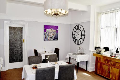 a dining room with two tables and a clock on the wall at Avenue Guest House in Blackpool