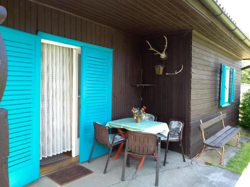 フェルラッハにあるFerienhaus Abhau-Tageの青いドア、テーブルと椅子付きのパティオ