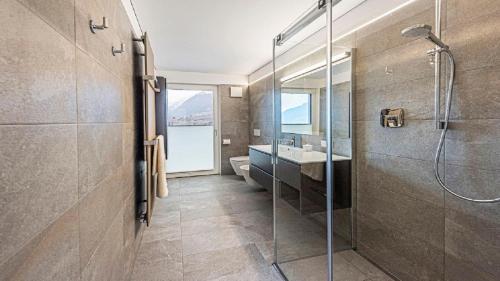 uma casa de banho com uma cabina de duche em vidro e um lavatório. em Penthouse Skygarden em Scena