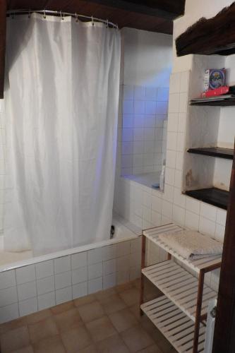 La salle de bains est pourvue d'un rideau de douche blanc et d'une baignoire. dans l'établissement Les gîtes du Mas Brunet, à Cadix