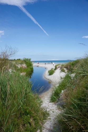 a beach with people on the sand and water at Strandhotel Balka Søbad in Neksø